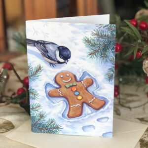 Holiday card of a gingerbreadman making a snow angel